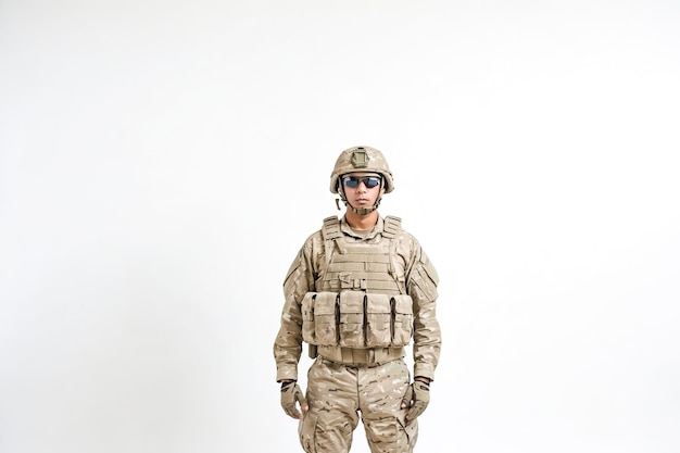 Photo portrait of a soldier in desert camouflage standing against a white background