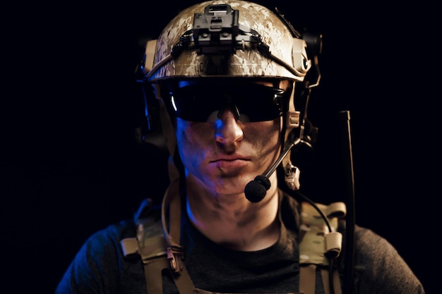 Portrait of special forces soldier in helmet and glasses in the dark