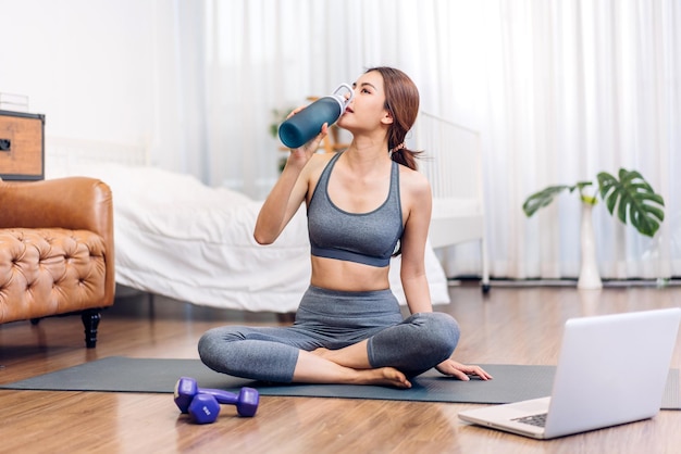 Portrait sport beauty body slim woman drinking water from a bottle while relax and feeling fresh at homeHealthy lifestyle concept