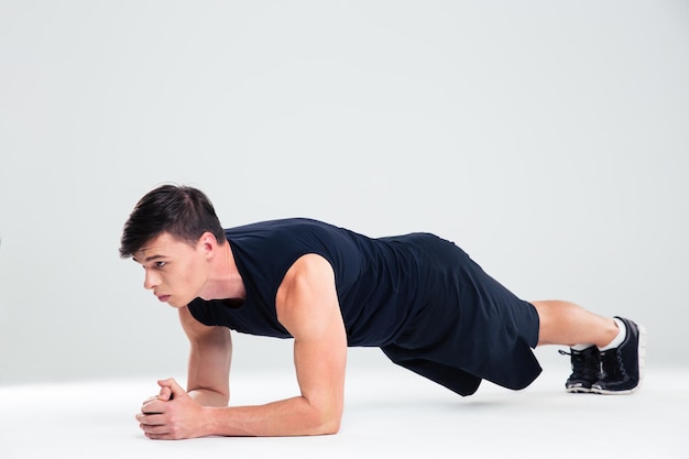 Portrait of a sports man doing elbow plank exercises isolated