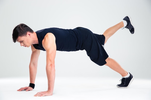 Portrait of a sports man doing warm up exercises isolated