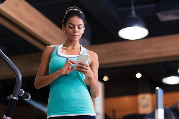 Portrait of a sports woman using smartphone in fitness gym