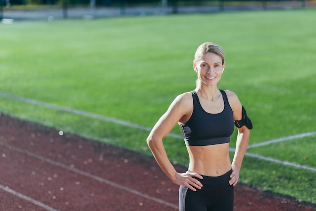 Portrait of sportswoman in sportswear at stadium blonde smiling and looking at camera woman before