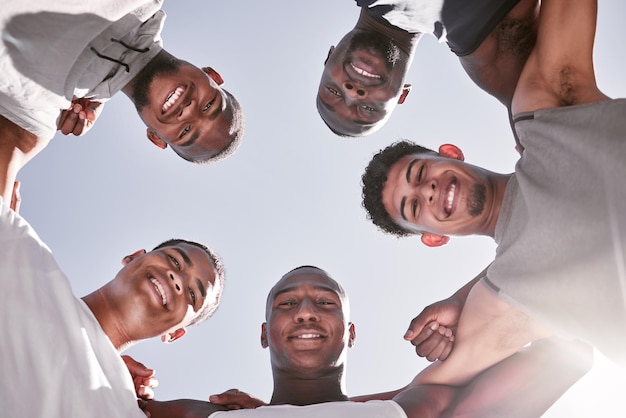 Portrait of sporty men from below joining in huddle for support and unity Group of cheerful friends and motivated athletes collaborating together in solidarity as a happy team and diverse community