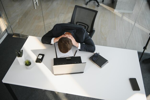 Portrait of stressed out and worried troublesome overworked businessman entrepreneur looking documents report in modern bright office working under pressure and tight deadline