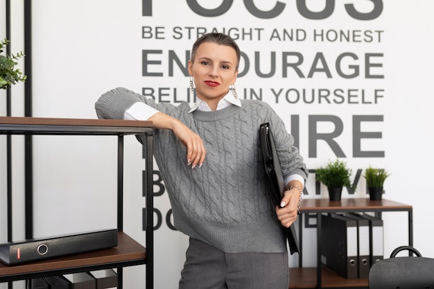 Portrait of a strong successful professional woman with a short haircut in the office with a folder