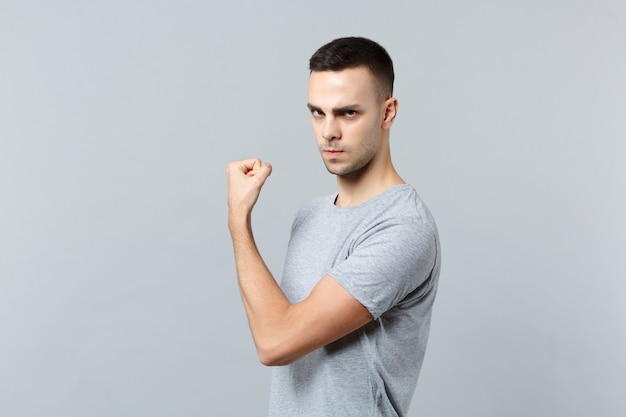 Portrait of strong young man in casual clothes, showing biceps, muscles