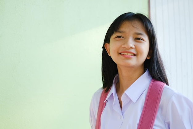 Portrait student young girl in uniform school and backpack on green background, Asian girl, Teenager.