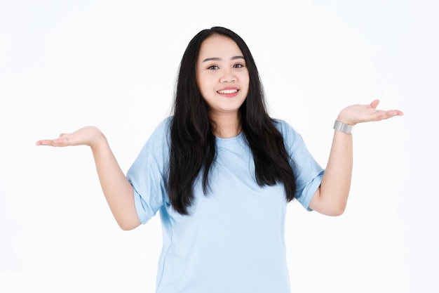 Portrait studio shot of Asian young chubby plump long black hair female model in blue casual t shirt and pose and in advetise action showing presenting product on white background.