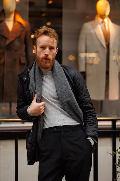 Portrait of a stylish bearded man against the background of elegant clothing store window