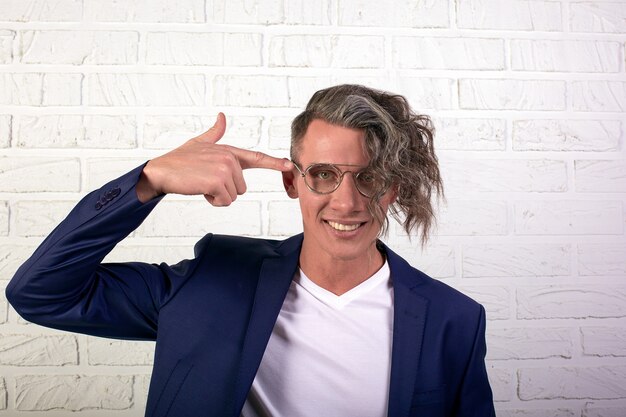 Portrait of stylish businessman with curly long hair in glasses looking at the camera on white