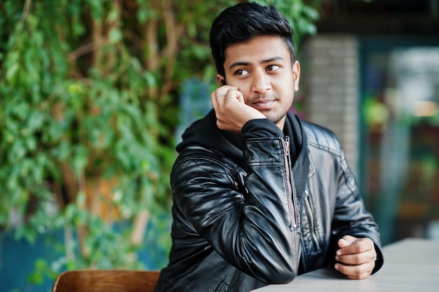 Portrait of stylish and casual young asian man wear on leather jacket spending time at cafe and speaking on mobile phone