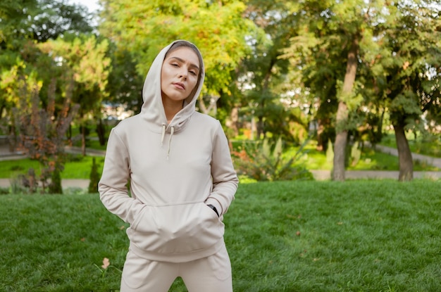 Portrait of a stylish fitness woman in a hood in a park outdoors Fitness concept