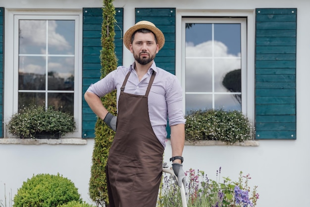 Portrait of stylish guygardener in plants garden handsome gardener during job outdoors