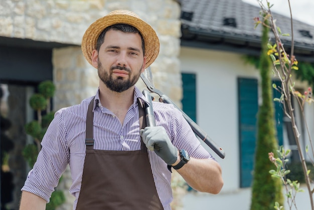 Portrait of stylish guygardener with garden scissors in plants garden