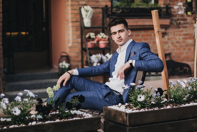 Portrait of stylish handsome young man with sitting outdoors. Businessman wearing jacket and watch.