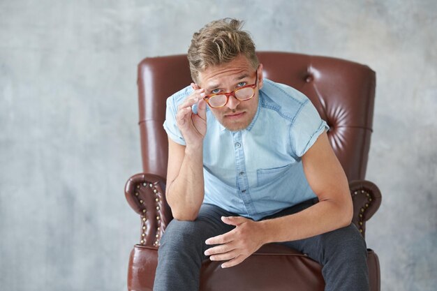 Portrait of a stylish intelligent man stares into the camera small unshaven charismatic blue shirt s