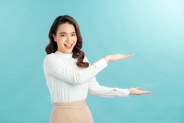 Portrait of stylish, nice, cute, modern woman in denim, casual outfit having empty place, copy space on her palm,