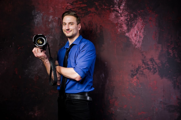 portrait of stylish professional photographer man with camera, wear on blue shirt and necktie.