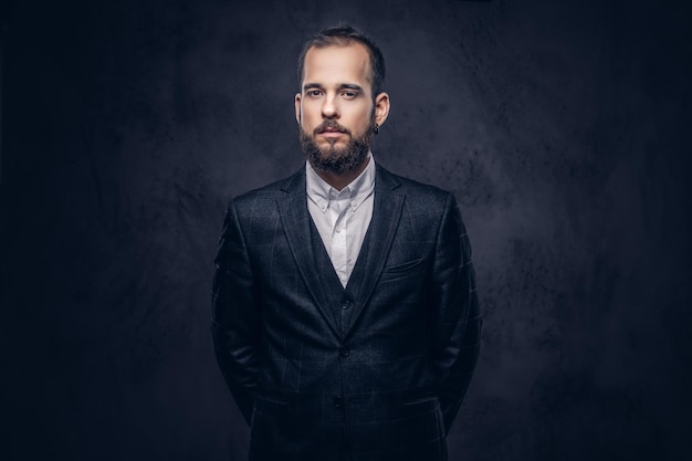 Portrait of a stylish serious bearded male, wearing an elegant suit on a dark background.