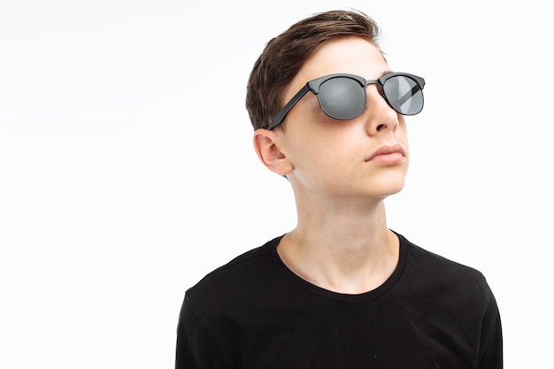 Portrait of a stylish teenager with sunglasses in a black shirt