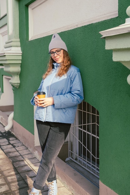 Portrait of a stylish woman in blue jacket with coffee cup spring outdoor portrait