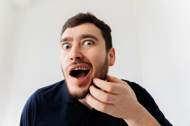 Portrait of a stylish young man scratches his beard and screams in pain annoying itch beard itching