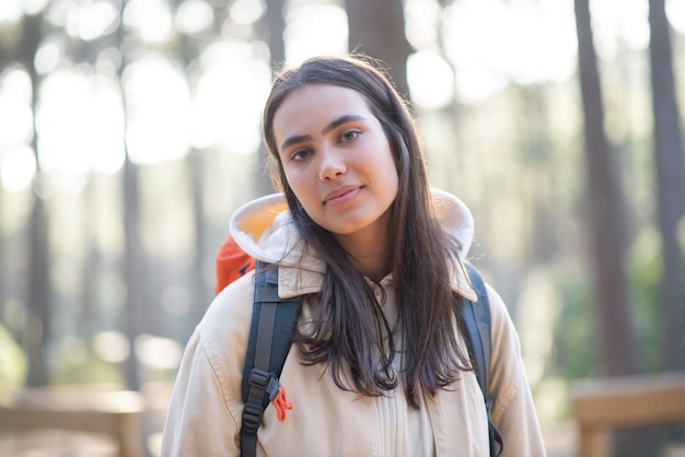 Portrait of stylish young woman in forest. Caucasian female woman with dark hair and green eyes looking at camera. Portrait, nature, beauty concept