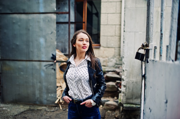 Photo portrait of stylish young woman wearing on leather jacket and ripped jeans at streets of city