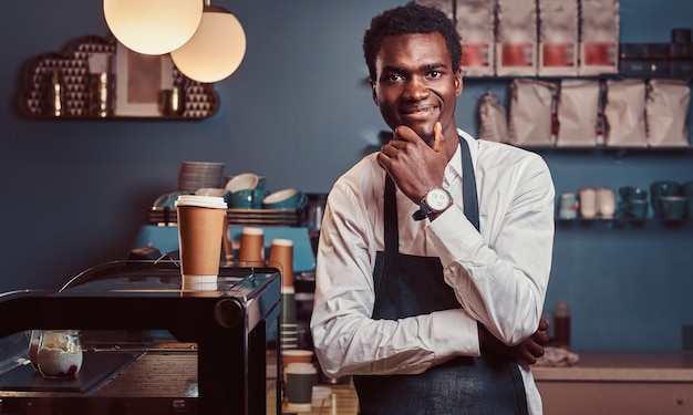 Portrait of successful African American owner small business smiling at camera while standing at coffee shop.