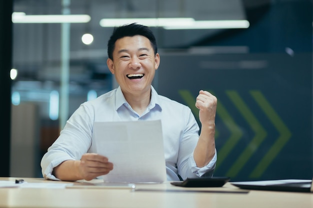 Portrait of successful asian businessman boss man smiling and looking at camera holding letter and