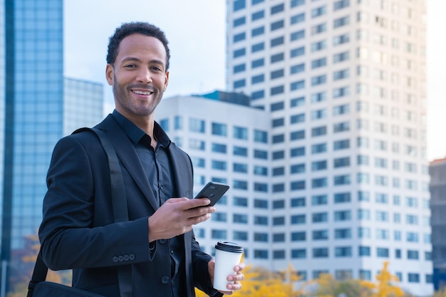 Portrait of successful black businessman in suit smiling looking at camera buildings in background