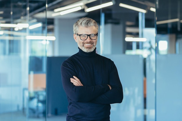 Portrait of successful businessman in modern office with crossed arms gray haired male investor