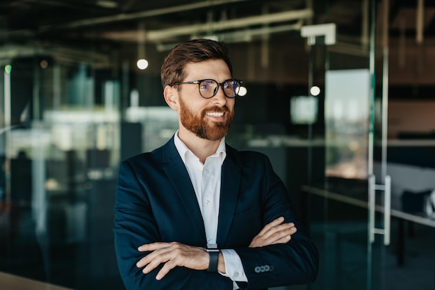 Portrait of successful businessman in suit posing with crossed hands looking away and smiling copy space