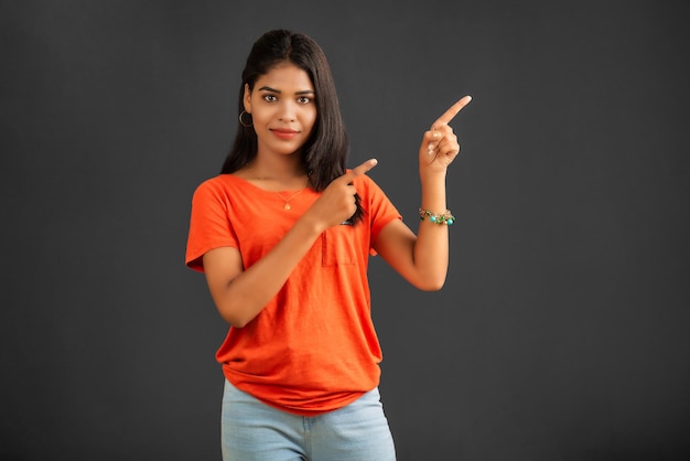 Portrait of a successful cheerful young girl pointing and presenting something with hand or finger with a happy smiling face