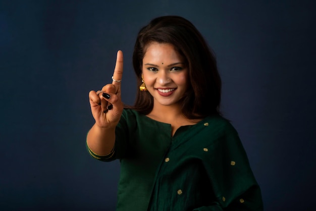 Portrait of a successful cheerful young girl presenting something with a fingers with a happy smiling face