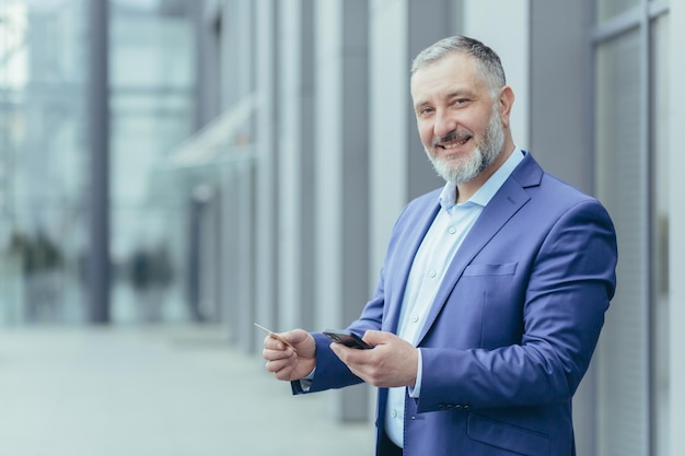 Portrait of successful grayhaired businessman man smiling and looking at camera boss holding bank