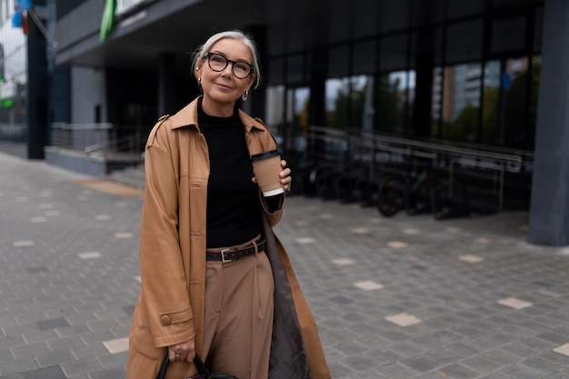 Portrait of a successful mature businesswoman with a cup of coffee at the entrance to the business