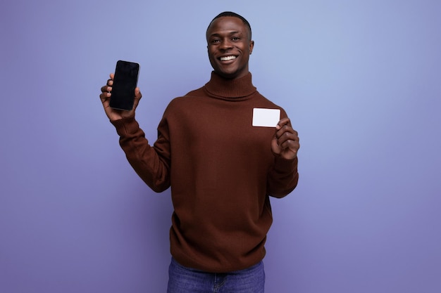 Portrait of successful young african man with plastic card and mobile phone isolated background with