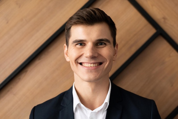 Portrait of a successful young businessman with a smile on his face against the wall in the office