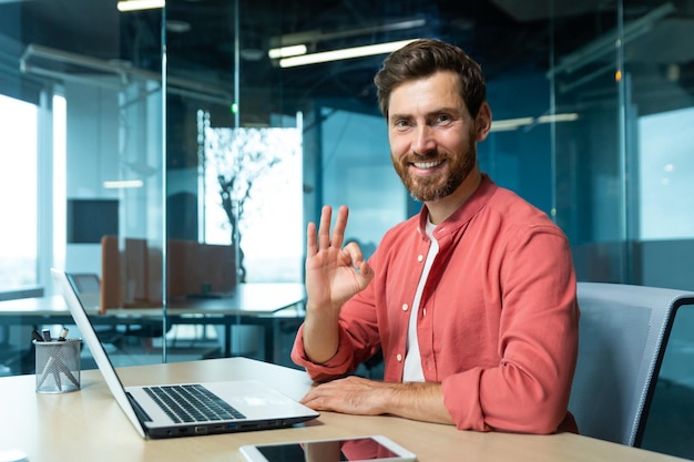 Portrait of a successful young man programmer designer freelancer in a red shirt sitting and working