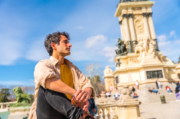 Portrait of a summer caucasian young man next to a city sculpture enjoying vacation