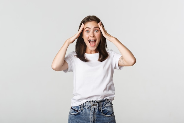 Portrait of surprised attractive girl looking excited and smiling amazed on white