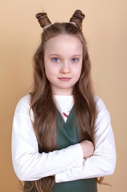 Portrait of a surprised cute little girl with long hair on a beige background I look into the camera Advertising of children's goods