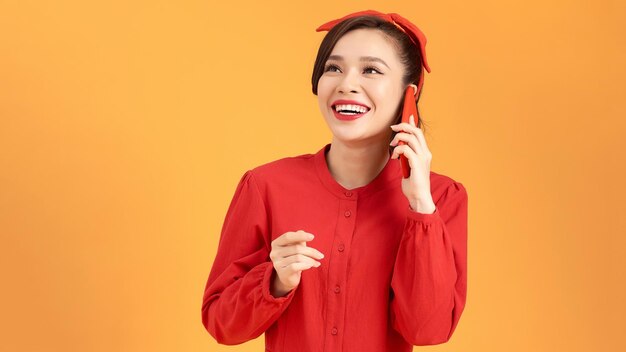 Portrait of a surprised girl talking on mobile phone isolated over yellow background