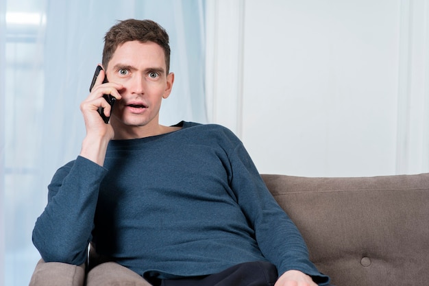 Portrait of surprised shocked guy handsome young man with wide open eyes and mouth is talking on