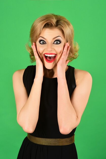 Portrait of surprised woman in black dress girl in black dress evening make up isolated on green