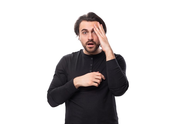 Portrait of surprised young handsome brunette man with hairstyle and beard dressed in black sweater