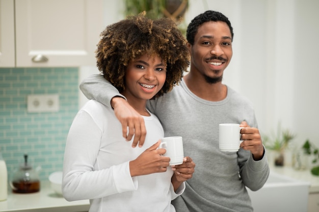 Portrait of sweet african american couple drinking coffee at kitchen