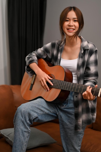 Portrait A talented and hipster young Asian woman sings while playing her acoustic guitar